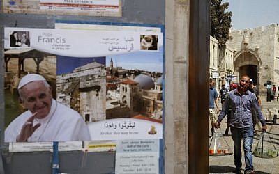 A juice vendor walks past a poster of Pope Francis in Jerusalem's Old City on May 20, 2014 a few days ahead of a the top-level visit by the Pope to the Holy Land. (photo credit: AFP/GALI TIBBON)