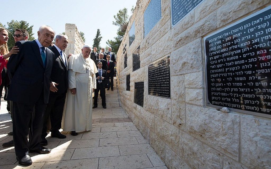 A handout picture released by the Vatican press office shows Pope Francis, looking at a memorial alongside Israeli President Shimon Peres, left, and Israeli Prime Minister Benjamin Netanyahu, second left, at Mount Herzl in Jerusalem on May 26, 2014. (photo credit: AFP/ OSSERVATORE ROMANO)