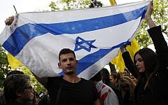 A man and a woman hold an Israeli flag during a demonstration called by French Jewish associations in front of the Belgian Embassy in Paris, on May 25, 2014, to protest against the attack that killed four people the day before at the Jewish Museum in Brussels. (photo credit: AFP/Thomas Samson)