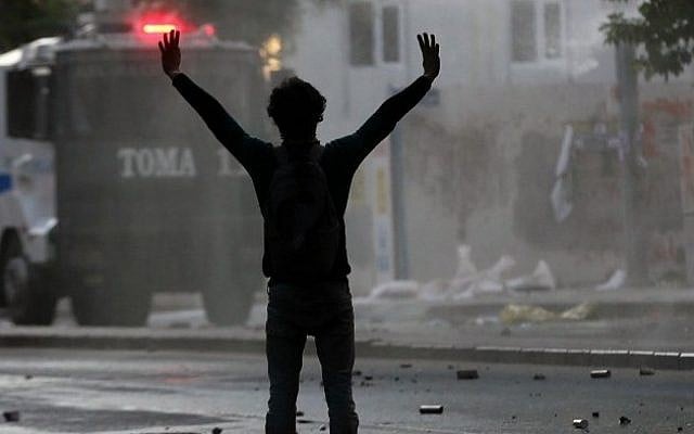 A protester raises his arms at a Turkish riot police vehicule while its firing water at protesters on May 31, 2014 in Ankara, as they mark the first anniversary of last year anti-government demonstrations. (Photo credit: AFP/ ADEM ALTAN)