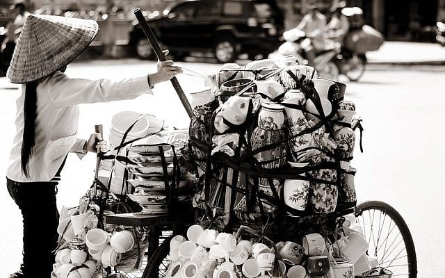 A woman selling goods from her bike in Hanoi. photo credit: CC BY Nathan Onions, Flickr)