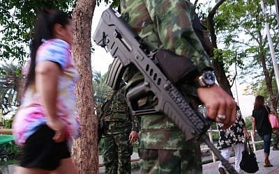 Pedestrians stroll past armed Thai soldiers guarding outside the Centre for the Administration of Peace and Order (CAPO) after soldiers were sent in to seize the center on Tuesday, May 20, 2014 in Bangkok, Thailand. (photo credit: AP Photo/Wason Wanichakorn) Pedestrians stroll past armed Thai soldiers guarding outside the Centre for the Administration of Peace and Order (CAPO) after soldiers were sent in to seize the center on Tuesday, May 20, 2014 in Bangkok, Thailand. (photo credit: AP Photo/Wason Wanichakorn)