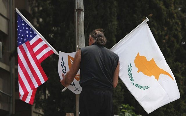 A municipality worker places a US flag, left and Cypriot flag, on an electricity column, on a street in divided capital Nicosia, Cyprus, Tuesday, May 20, 2014. (photo credit: AP/Petros Karadjias) A municipality worker places a US flag, left and Cypriot flag, on an electricity column, on a street in divided capital Nicosia, Cyprus, Tuesday, May 20, 2014. (photo credit: AP/Petros Karadjias)