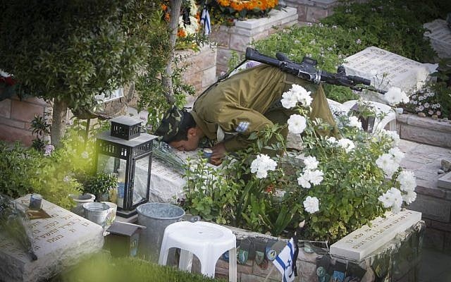 An Israeli soldier kisses the grave of a fallen soldier at the Mt Herzl military cemetery in Jerusalem on May 05, 2014. (Photo credit: Miriam Alster/Flash90)