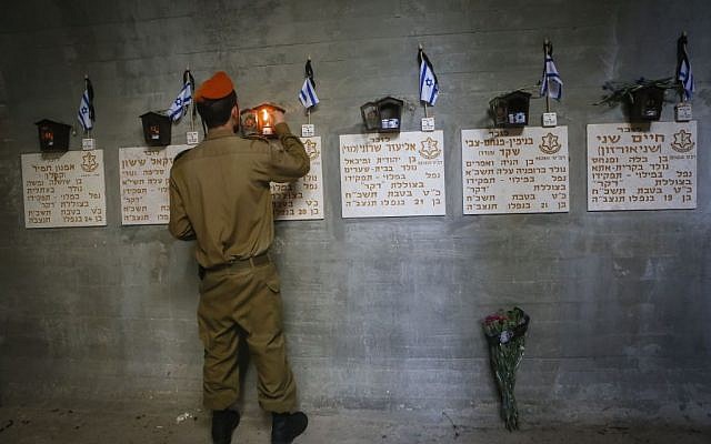 An Israeli soldier lights candles next to the names of Israeli fallen soldiers at the Dakar submarine monument, at the Mt Herzl military cemetery in Jerusalem on May 05, 2014. (Miriam Alster/Flash90)