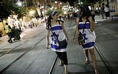 Young women wrapped in Israeli flags walking the streets of Jerusalem as Israel's celebrates its 66th Independence Day on May 05, 2014. (Photo credit: Miriam Alster/FLASH90)