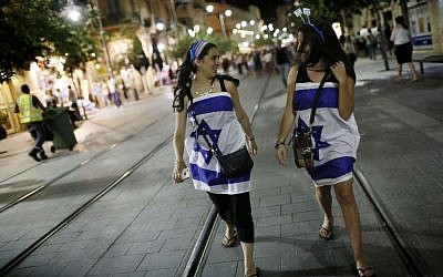 Young women wrapped in Israeli flags walking the streets of Jerusalem as Israel's celebrates its 66th Independence Day on May 05, 2014. (Photo credit: Miriam Alster/FLASH90)