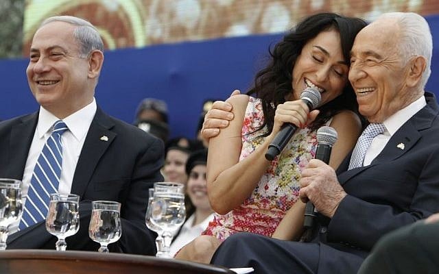 Then-President Shimon Peres (R) and Prime Minister Benjamin Netanyahu sing along with Iranian-born singer Rita as they participate in a ceremony for outstanding soldiers as part of Israel's 66th Independence Day celebrations, at the President's residence in Jerusalem, Tuesday, May 06, 2014. (photo credit: Miriam Alster/Flash90) 