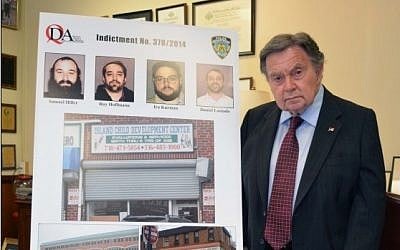 Queens District Attorney Richard A. Brown stands next to pictures of the 4 men indicted for stealing from a Far Rockaway special needs school  (photo credit: Courtesy/Queens District Attorney)