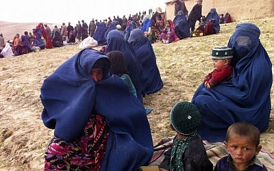 Survivors sit on a hillside as others watch the rescue effort near the site of Friday's landslide that buried Abi-Barik village in Badakhshan province, northeastern Afghanistan, Saturday, May 3, 2014.  (Photo credit: AP/Amir Shah)