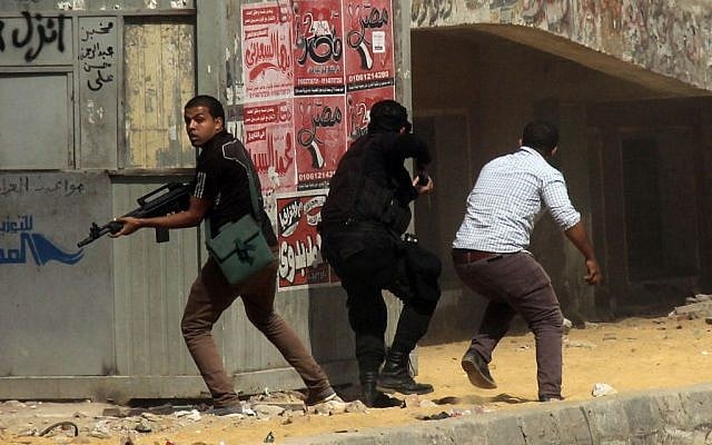 Members of the Egyptian security forces hold guns during clashes with supporters of the Muslim Brotherhood outside Al-Azhar University in Cairo, Egypt, Friday, May 23, 2014 (photo credit: AP/Ahmed Taranh) Members of the Egyptian security forces hold guns during clashes with supporters of the Muslim Brotherhood outside Al-Azhar University in Cairo, Egypt, Friday, May 23, 2014 (photo credit: AP/Ahmed Taranh)