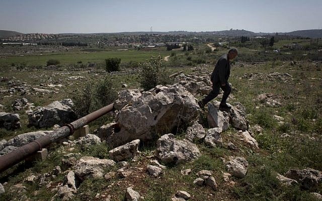 In this April 17, 2014 photo, Abdel Rahman Saleh, the mayor of the Palestinian village of Silwad, inspects his village's land dedicated by the Israeli settlement of Ofra, seen in the background, for an illegal wastewater treatment plant, north of the West Bank city of Ramallah. (photo credit: AP/Nasser Nasser)