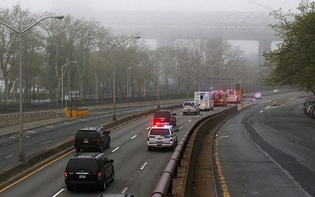 Part of the Williamsburg Bridge peeks through thick morning fog as police and fire department vehicles lead a procession along Franklin D. Roosevelt East River Drive with the unidentified remains of victims of the Sept. 11, 2001 attacks as they are returned to the World Trade Center site, Saturday, May 10, 2014, in New York. (Photo credit: AP/Julio Cortez)