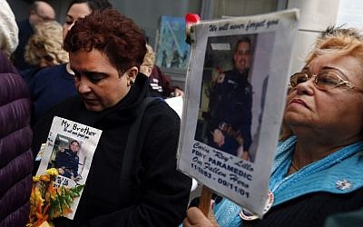 Iliana Flores, left, and her mother Ilia Rodriguez hold photos of Carlos Lillo, Iliana's brother and Ilia's son, as they join other family members of victims of the of the Sept. 11, 2001 attacks in protest of the transfer of unidentified remains of those killed at the World Trade Center from the Office of the Chief Medical Examiner to the World Trade Center site, Saturday, May 10, 2014, in New York. (Photo credit: AP/Jason DeCrow)
