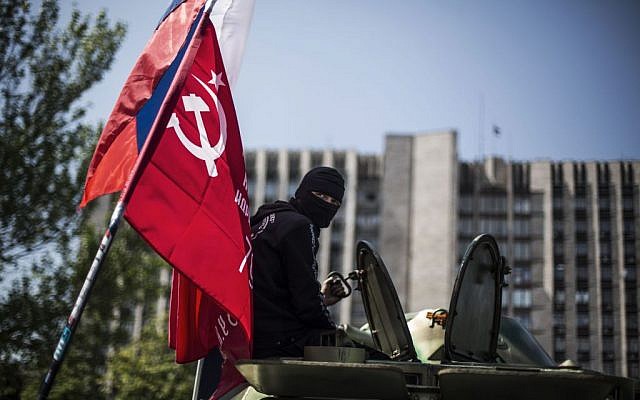 A masked pro Russia man is seen atop an APC flying a Russian flag, top, and a Donetsk People's Republic flag, as it stands in front of the occupied administration building in Donetsk, Ukraine, Saturday, May 10, 2014 (photo credit: AP/Manu Brabo) A masked pro Russia man is seen atop an APC flying a Russian flag, top, and a Donetsk People's Republic flag, as it stands in front of the occupied administration building in Donetsk, Ukraine, Saturday, May 10, 2014 (photo credit: AP/Manu Brabo)