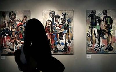 A woman looks at a series of three acrylic on canvas paintings named Hamamah, by Palestinian artist Ismail Dahlan, May 10, 2014 (photo credit AP/Nasser Nasser)