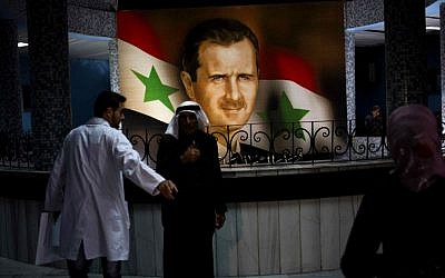 People walk through the Damascus General Hospital past a portrait of the President Bashar Assad in Damascus, Syria, Sunday, May 4, 2014. (photo credit: AP Photo/Dusan Vranic) People walk through the Damascus General Hospital past a portrait of the President Bashar Assad in Damascus, Syria, Sunday, May 4, 2014. (photo credit: AP Photo/Dusan Vranic)