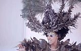 The hair peacock perched on the model's head opens its wings via remote control and breathes smoke. (YouTube screenshot)