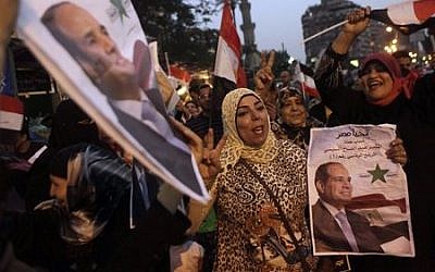 Supporters of presidential candidate former army chief Abdel-Fattah el-Sissi hold his posters and wave national flags as they celebrate during the second day of presidential elections in Cairo, Egypt, Tuesday, May 27, 2014. (photo credit: AP Photo/Amr Nabil)