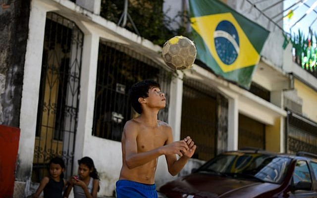 A young resident juggles a football in front of a Brazilian flag in Manaus on June 14, 1014.(photo credit: AFP/FABRICE COFFRINI) A young resident juggles a football in front of a Brazilian flag in Manaus on June 14, 1014.(photo credit: AFP/FABRICE COFFRINI)