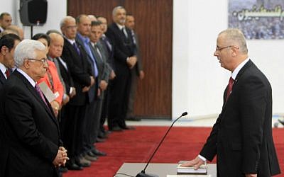 Palestinian Authority Prime Minister Rami Hamdallah (R) is sworn in along with the new Palestinian unity government in the presence of PA President Mahmoud Abbas (L) in the West Bank city of Ramallah, Monday, June 2, 2014 (photo credit: AFP/ABBAS MOMANI)