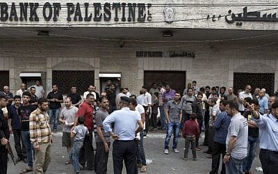 Hamas security forces in Gaza City stand guard as employees paid by the Palestinian Authority wait to receive their salaries outside a closed bank, on Thursday, June 5, 2014. (AFP/Mohammed Abed)