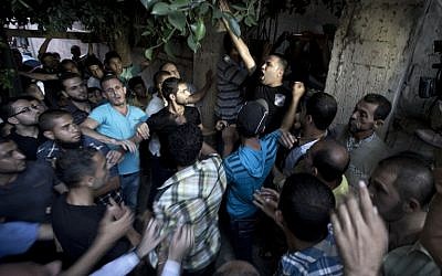Palestinian mourners shout as the wait to carry the body of Ali al-Awour, 7, during his funeral in Beit Lahia, in the northern Gaza Strip, on Saturday, June 14, 2014. Awour, who was wounded in an Israeli air raid on June 11 in the northern Gaza Strip, died of his wounds, a spokesman for the Palestinian health services said. (photo credit: AFP/MAHMUD HAMS)