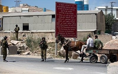 Israeli soldiers man a checkpoint in the West Bank city of Hebron on Sunday, June 15, 2014, as Israel broadened the search for three teenagers believed kidnapped by terrorists (photo credit: AFP/MENAHEM KAHANA)