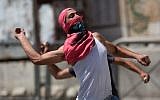 Palestinians throw stones at Israeli forces (unseen) during clashes in the center of the West Bank town of Hebron on June 16, 2014. (photo credit: Menahem Kahana/AFP)