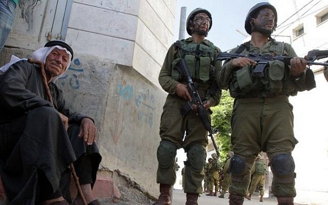 An elderly Palestinian man sits near Israeli soldiers taking part in a search operation for three Israeli teenagers believed kidnapped by Palestinian militants, on June 18, 2014 in the West Bank village of Tapuah, west of Hebron. photo credit: AFP/HAZEM BADER) An elderly Palestinian man sits near Israeli soldiers taking part in a search operation for three Israeli teenagers believed kidnapped by Palestinian militants, on June 18, 2014 in the West Bank village of Tapuah, west of Hebron. photo credit: AFP/HAZEM BADER)