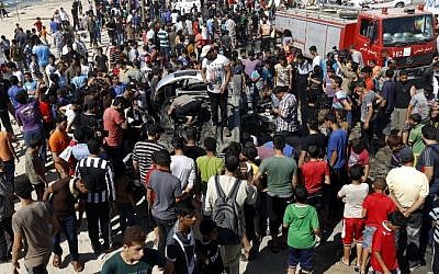 Palestinians gather around a car that was targeted by an Israeli air strike in Gaza City on June 27, 2014.  (Photo credit: AFP / MOHAMMED ABED)