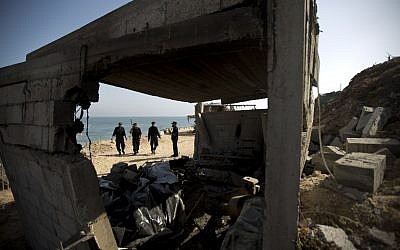 Palestinian security personnel inspect a damaged building following overnight Israeli air raids in the central Gaza Strip on June 28, 2014. (photo credit: AFP PHOTO/MAHMUD HAMS)