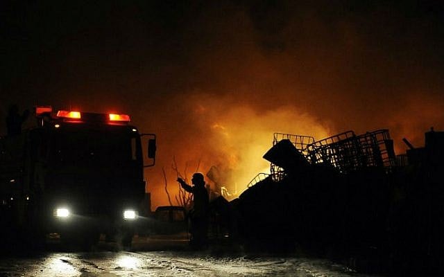 Israeli firefighters extinguish a burning factory hit by a rocket fired from the Gaza Strip on June 28, 2014 at an industrial zone in the southern city of Sderot. The previous day two Palestinians in the Gaza Strip were killed in an Israeli air raid after a bomb exploded near troops manning Israel's security fence. (photo credit: AFP/David Buimovitch)