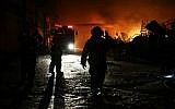 Israeli firefighters extinguish a burning factory hit by a rocket fired from the Gaza Strip on June 28, 2014 at an industrial zone in the southern city of Sderot. The previous day two Palestinians in the Gaza Strip were killed in an Israeli air raid after a bomb exploded near troops manning Israel's security fence. (photo credit: AFP/David Buimovitch)