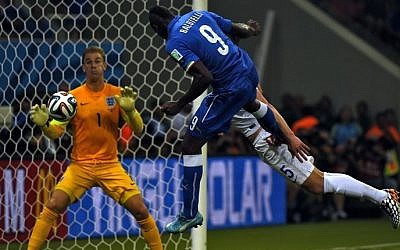 Italy's forward Mario Balotelli (C) heads the ball to score a goal as England's goalkeeper Joe Hart (L) and England's defender Gary Cahill try to defend during a Group D soccer match between England and Italy at the Amazonia Arena in Manaus during the 2014 FIFA World Cup on June 14, 2014 (photo credit: AFP/FABRICE COFFRINI)