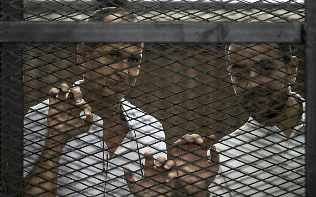 Al-Jazeera channel's Australian journalist Peter Greste (left) and Egyptian journalist Mohamed Baher stand inside the defendants cage during their trial for allegedly supporting the Muslim Brotherhood at the police institute near Cairo's Tora prison on June 1, 2014. (photo credit: AFP/Khaled Desouki) Al-Jazeera channel's Australian journalist Peter Greste (left) and Egyptian journalist Mohamed Baher stand inside the defendants cage during their trial for allegedly supporting the Muslim Brotherhood at the police institute near Cairo's Tora prison on June 1, 2014. (photo credit: AFP/Khaled Desouki)
