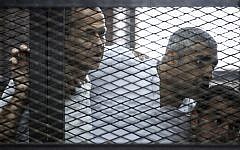 Al-Jazeera news channel's Australian journalist Peter Greste (L) and his colleagues, Egyptian-Canadian Mohamed Fadel Fahmy (C) and Egyptian Baher Mohamed, listen to the verdict inside the defendants cage during their trial for allegedly supporting the Muslim Brotherhood on June 23, 2014 at the police institute near Cairo's Tora prison. (Khaled Desouki/AFP)