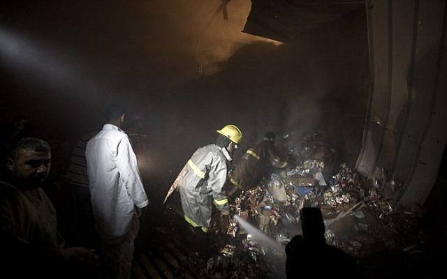 Palestinians and firemen inspect a food store following an air strike by the Israeli Air Force on Gaza City on June 20, 2014. (photo credit: Mahmud Hams/AFP) Palestinians and firemen inspect a food store following an air strike by the Israeli Air Force on Gaza City on June 20, 2014. (photo credit: Mahmud Hams/AFP)