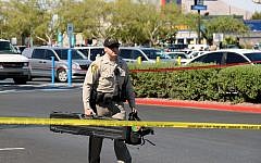 A Las Vegas Metropolitan Police Department officer removes equipment from a Wal-Mart on June 8, 2014 in Las Vegas, Nevada. Two officers were reported shot and killed by two assailants at a pizza restaurant near the Wal-Mart. The two suspects then reportedly went into the Wal-Mart where they killed a third person before killing themselves. (photo credit: Ethan Miller/Getty Images/AFP)