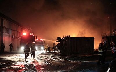 Israeli firefighters try to extinguish a burning factory hit by a rocket fired by Palestinian terrorists from the Gaza Strip in the southern Israeli town of Sderot, Saturday, June 28, 2014. (phot credit: AP Photo/ Tsafrir Abayov)