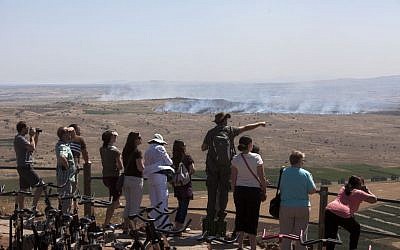 Israelis and tourists look at smoke from fires caused by fighting in Syria from an observation point on Mt. Bental in the Golan Heights, June 7, 2013 (photo credit: AP/Sebastian Scheiner)