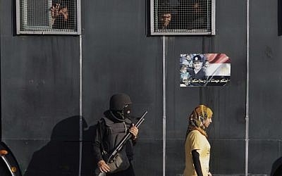 An Egyptian woman walks past a vehicle carrying anti-riot police officers deployed to secure a protest against sexual harassment in Cairo, Egypt, Saturday, June 14, 2014 (photo credit: AP/Amr Nabil)