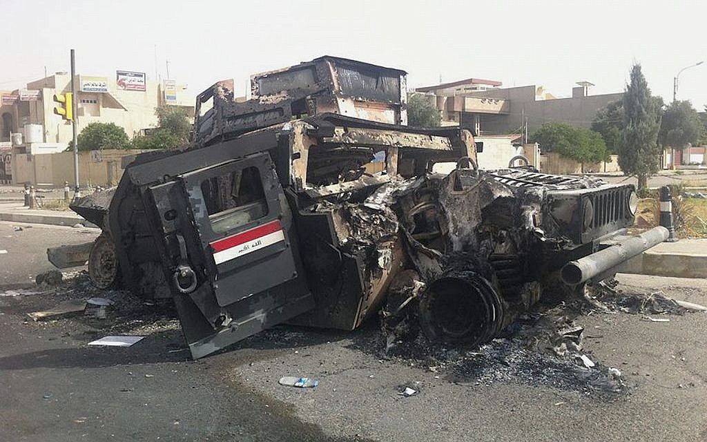 An Iraqi army armored vehicle is seen burned on a street of the northern city of Mosul, Iraq, Thursday, June 12, 2014 (photo credit: AP) An Iraqi army armored vehicle is seen burned on a street of the northern city of Mosul, Iraq, Thursday, June 12, 2014 (photo credit: AP)