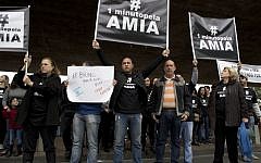 People hold up signs after a minute of silence as the Argentina-Iran World Cup game kicks off in Sao Paulo, Brazil, Saturday, June 21, 2014. The protest was held to mark 20 years since the unsolved bombing attack against a Buenos Aires Jewish center that left 85 dead. Prosecutors blame Iran for the attack. The hashtag reads in Portuguese "One minute for the AMIA," which stands for "Israeli Argentine Mutual Association," the Jewish community center of Buenos Aires. (Photo credit: AP/Dario Lopez-Mills)