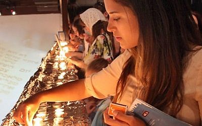 A young woman lights the Shabbat candles during preparation for setting a Guinness World record of the largest Shabbat dinner in the world, organized by "White City Shabbat" and held at the Tel Aviv port on June 13, 2014.  (Photo credit: Gideon Markowicz/FLASH90)