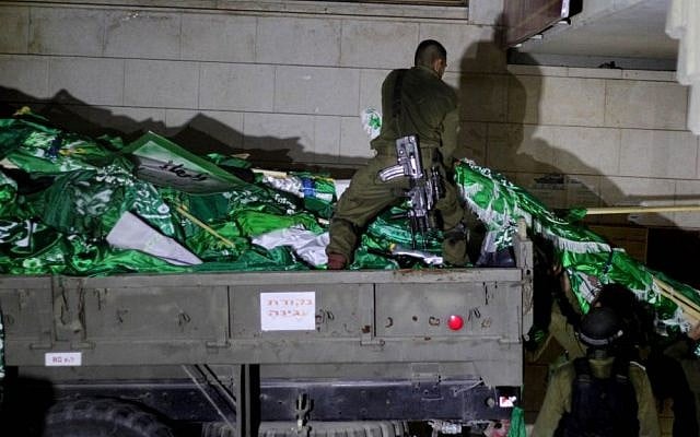 Israeli soldiers seen loading Hamas flags onto an army truck during a patrol at Birzeit University, on the outskirts of the city of Ramallah in the West Bank, during an operation on June 19, 2014. (photo credit: Issam Rimawi/Flash 90)
