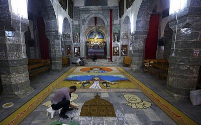 An Iraqi works on a temporary mosaic of Christian symbols made from the area's produce, including wheat, beans and lentils to commemorate an upcoming harvest feast, at the Chaldean Church of the Virgin Mary of the Harvest, in Alqosh,  June 15, 2014. (photo credit: AP)