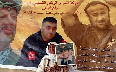Palestinian Ameeneh Nazzal, 75, holds a photo of her son, Ahmed, who she says is held in an Israeli jail, during a demonstration in support of Palestinian prisoners on a hunger strike, in the West Bank city of Jenin, June 3, 2014. (photo credit: AP/Mohammed Ballas)