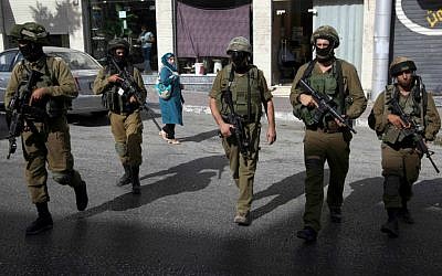 Illustrative photo of IDF soldiers walking on a street in the West Bank city of Hebron, June 19, 2014. (AP/Majdi Mohammed)
