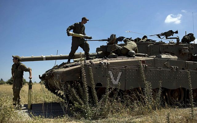 Israeli soldiers load shells into their tank following the first death on the Israeli side of the Golan since the eruption of the Syrian civil war more than three years ago, near the Israeli village of Alonei Habashan, June 22, 2014 (AP/Oded Balilty) Israeli soldiers load shells into their tank following the first death on the Israeli side of the Golan since the eruption of the Syrian civil war more than three years ago, near the Israeli village of Alonei Habashan, June 22, 2014 (AP/Oded Balilty)